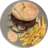 Burger BBQ-Puten-Rib mit Gewürzgurke, roten Zwiebeln und Eisberg (1,2,9,15,19,21,22,81,83) dazu als Menüoption Pommes und House-Dip (9,22)