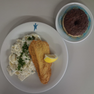 Gebackenes Schollenfilet mit Zitronenkeil (16,81,82) dazu hausgemachter Kartoffelsalat mit Radieschen, Gewürzgurke und Rucola (9,15,19,81) und 1 Donut (19,81)
