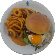 'Beef & Egg Burger' mit saftigem Rindfleisch, Spiegelei, Eisberg, Zwiebeln und Tomaten (1,2,9,15,19,21,22,81) dazu Twister Pommes (81)